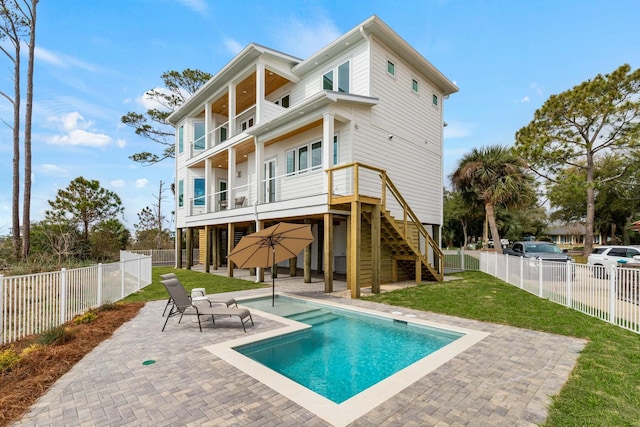 back of property featuring a balcony, a patio area, a fenced backyard, and a yard