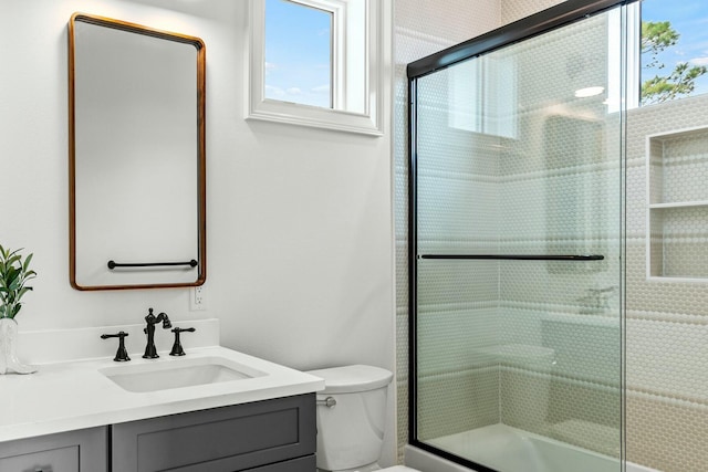 full bathroom featuring a shower with door, vanity, and toilet