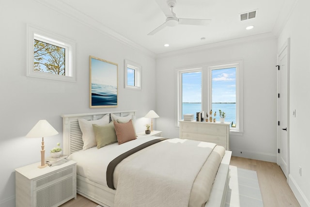 bedroom with light wood finished floors, baseboards, visible vents, and crown molding