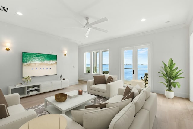 living room with light wood finished floors, visible vents, a water view, crown molding, and recessed lighting