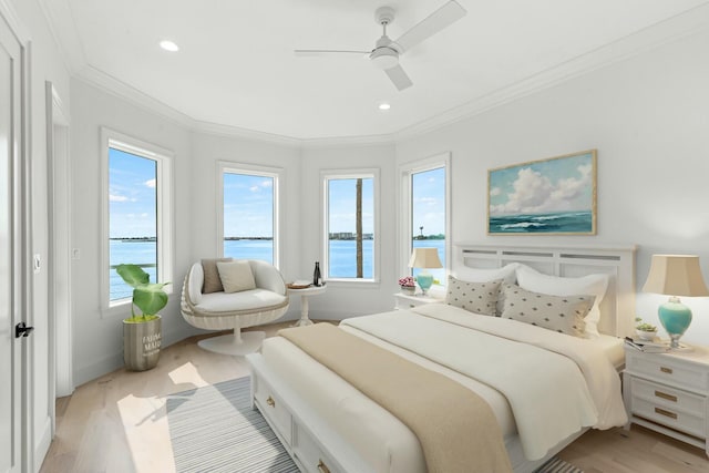 bedroom with ornamental molding, a water view, light wood-style floors, and a ceiling fan