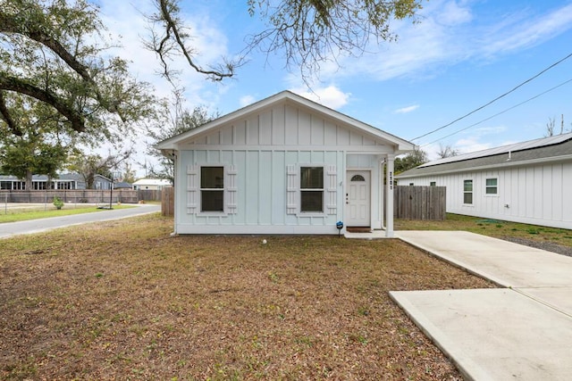 view of front facade with a front lawn, board and batten siding, and fence