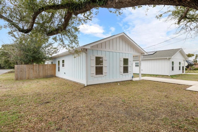 view of front of property featuring fence, a front lawn, and board and batten siding