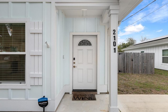 entrance to property featuring board and batten siding and fence