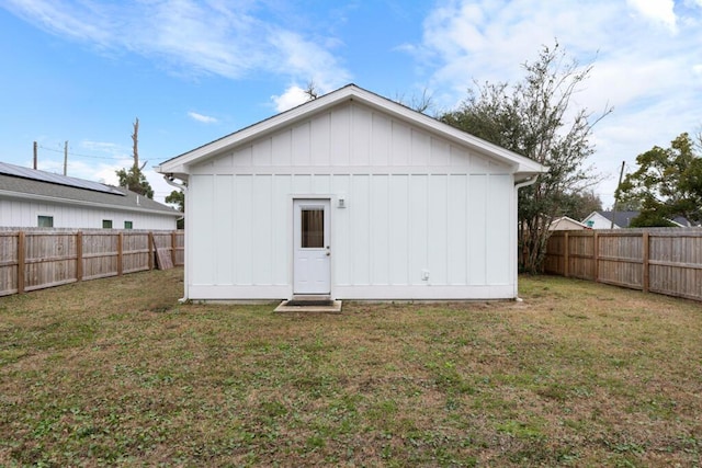 back of house featuring a fenced backyard, an outdoor structure, board and batten siding, and a yard