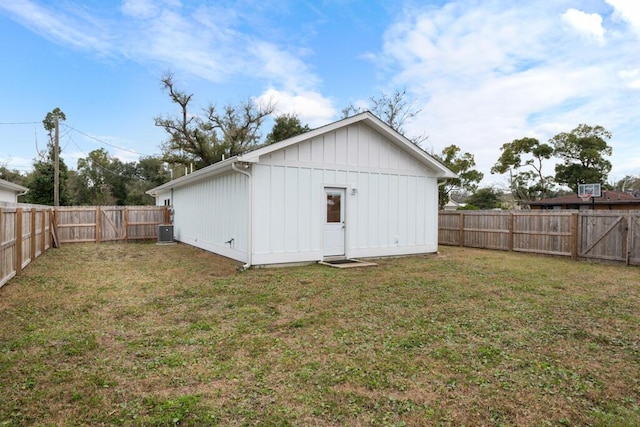 rear view of property with central air condition unit, board and batten siding, a fenced backyard, and a lawn