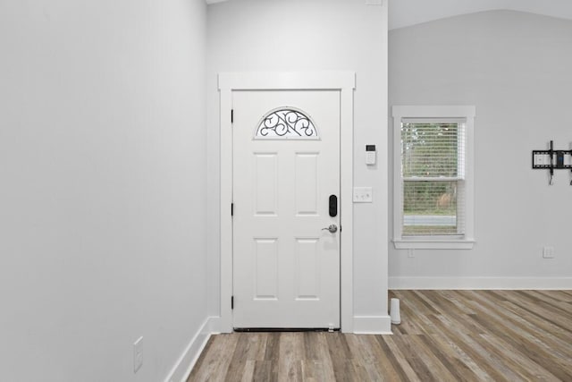 foyer entrance with vaulted ceiling, light wood-style flooring, and baseboards