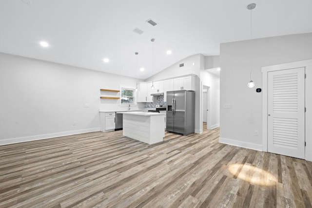 kitchen featuring decorative light fixtures, open shelves, stainless steel appliances, light countertops, and a kitchen island