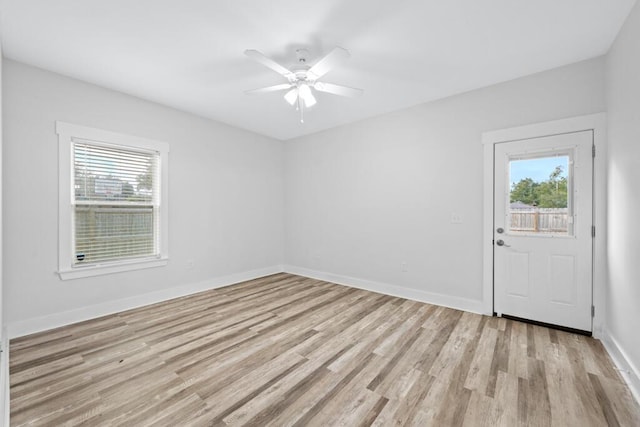 spare room featuring light wood finished floors, baseboards, and a wealth of natural light