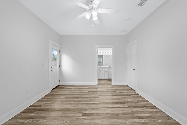 empty room with light wood-style floors, visible vents, baseboards, and a ceiling fan