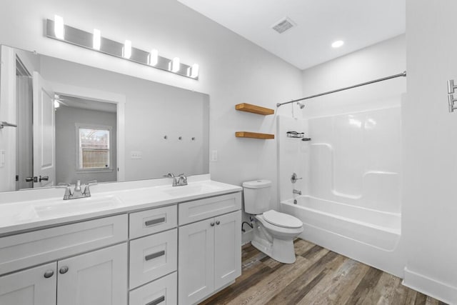 bathroom with bathtub / shower combination, visible vents, a sink, and wood finished floors