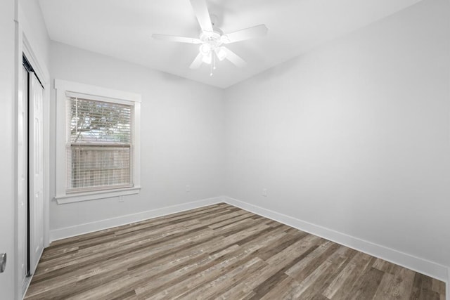 empty room with ceiling fan, baseboards, and wood finished floors