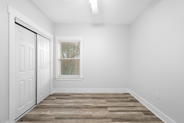 unfurnished bedroom with a ceiling fan, a closet, baseboards, and wood finished floors