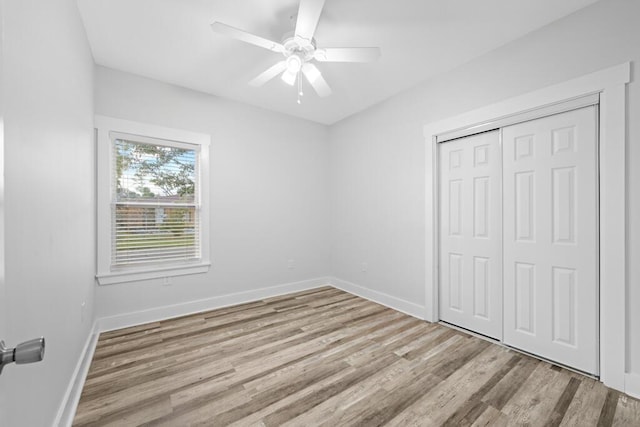 unfurnished bedroom featuring baseboards, ceiling fan, a closet, and light wood-style floors