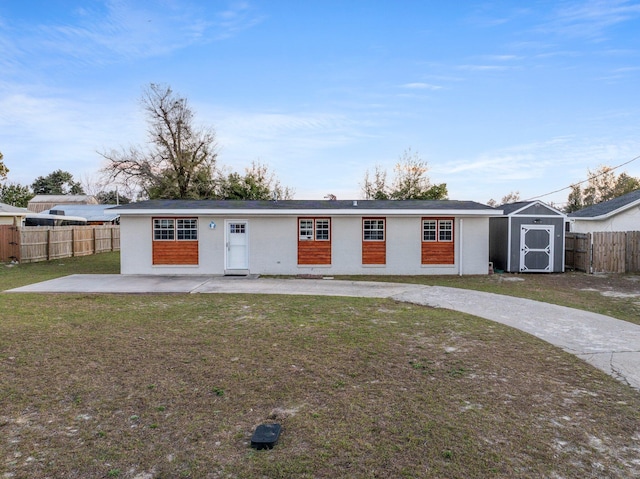 view of front of house with an outbuilding, a patio, a fenced backyard, a storage shed, and a front lawn