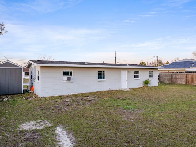 back of property featuring an outbuilding, a yard, concrete block siding, and fence