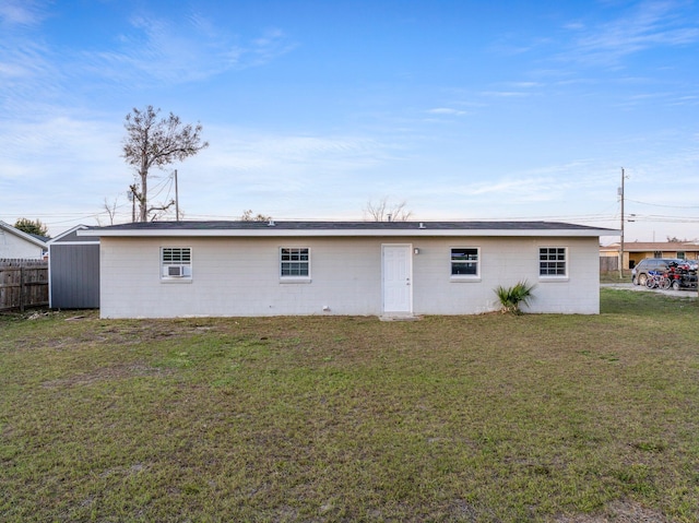 back of property with a lawn and fence