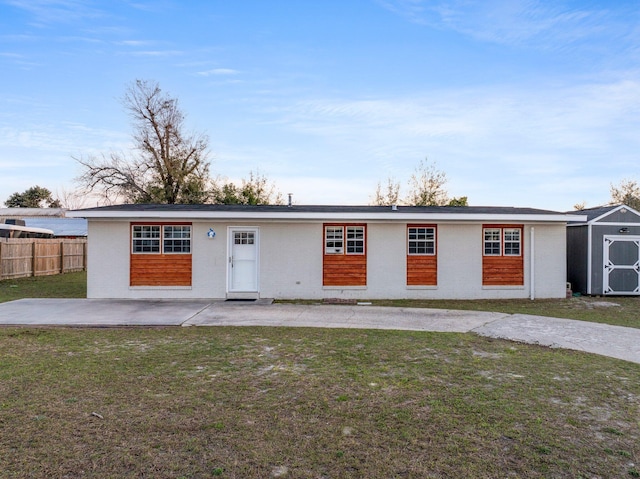 view of front of home featuring a patio, an outbuilding, fence, a shed, and a front yard