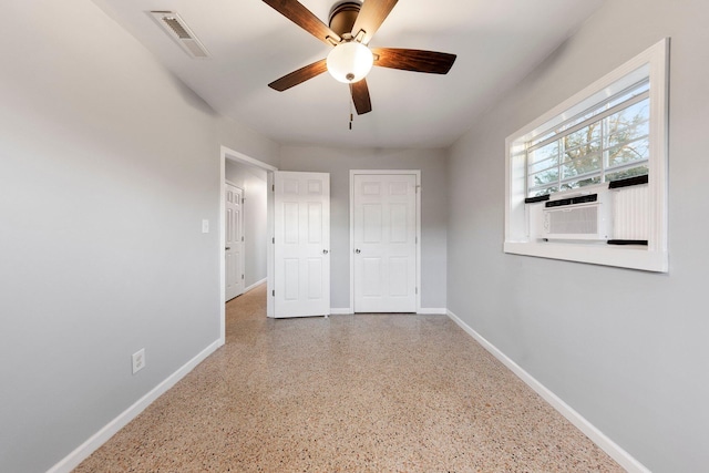 unfurnished bedroom featuring cooling unit, speckled floor, a ceiling fan, visible vents, and baseboards