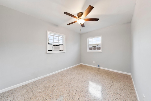 empty room with cooling unit, baseboards, a ceiling fan, and speckled floor