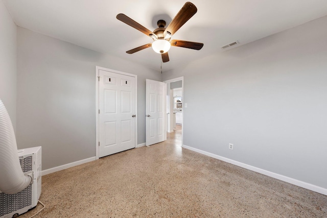 unfurnished bedroom featuring visible vents, ceiling fan, baseboards, and speckled floor