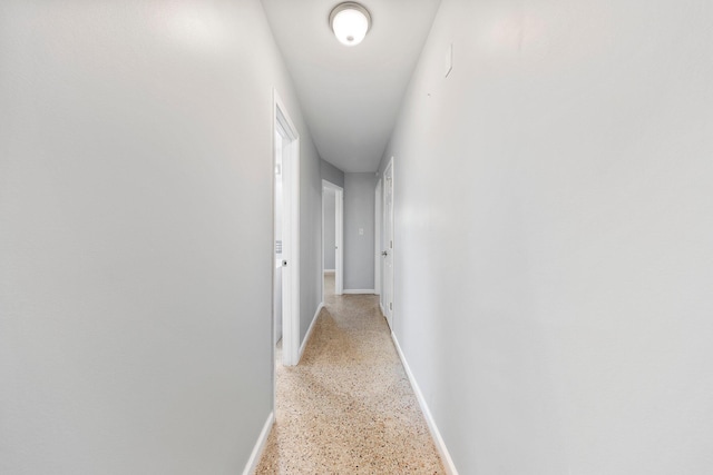 hall with light speckled floor and baseboards