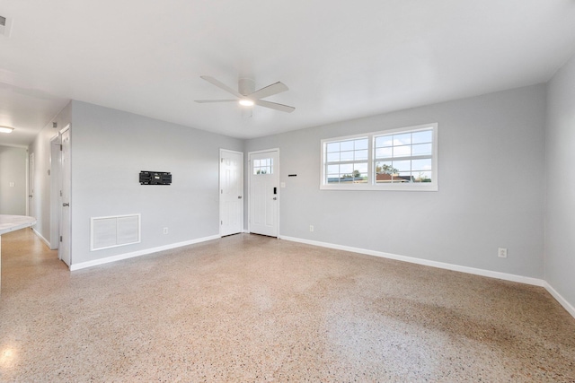 spare room with baseboards, visible vents, ceiling fan, and speckled floor