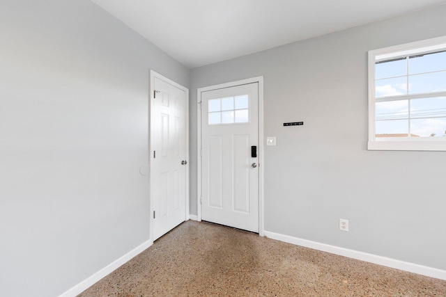 foyer featuring baseboards, speckled floor, and a healthy amount of sunlight