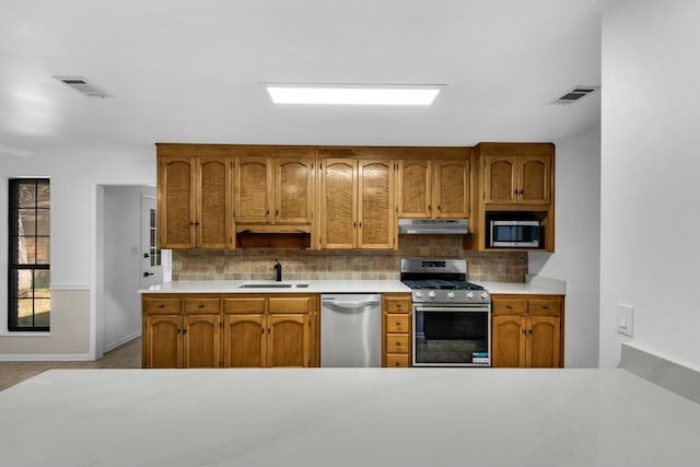 kitchen featuring visible vents, decorative backsplash, appliances with stainless steel finishes, a sink, and under cabinet range hood