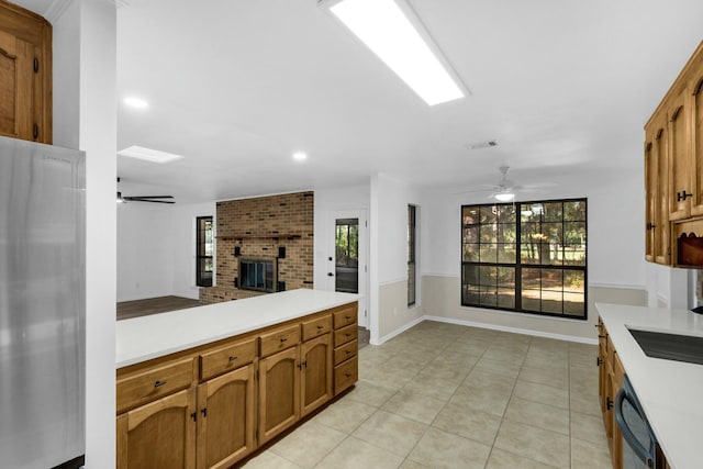 kitchen with brown cabinetry, freestanding refrigerator, open floor plan, and light countertops