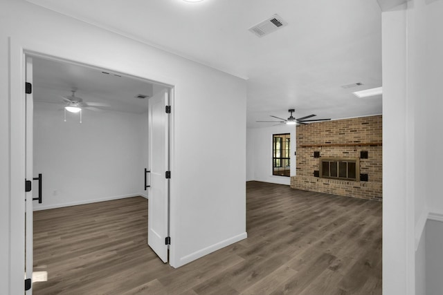 living room with a fireplace, wood finished floors, visible vents, baseboards, and a ceiling fan