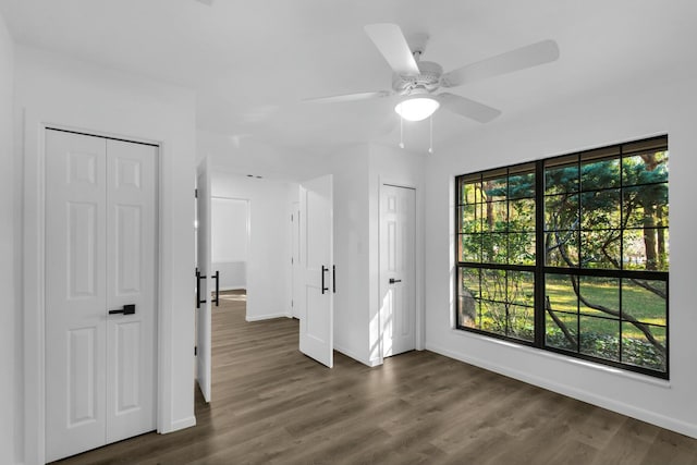 empty room with dark wood-type flooring, a wealth of natural light, and baseboards