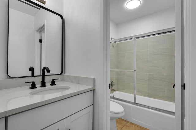 bathroom with toilet, tile patterned flooring, enclosed tub / shower combo, and vanity