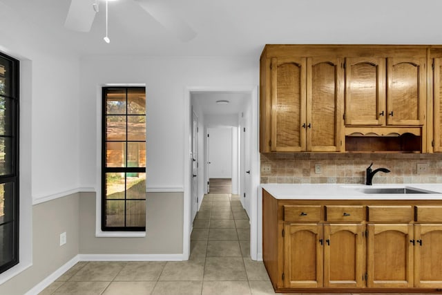 kitchen featuring tasteful backsplash, light countertops, brown cabinets, and a sink