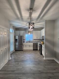 kitchen featuring white cabinets, light countertops, appliances with stainless steel finishes, dark wood-style floors, and pendant lighting