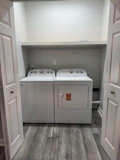 laundry room featuring laundry area, separate washer and dryer, and wood finished floors