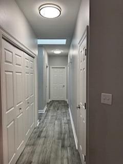 corridor featuring dark wood finished floors and baseboards