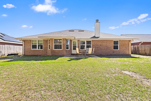 back of house with a chimney, a patio area, a fenced backyard, and a lawn