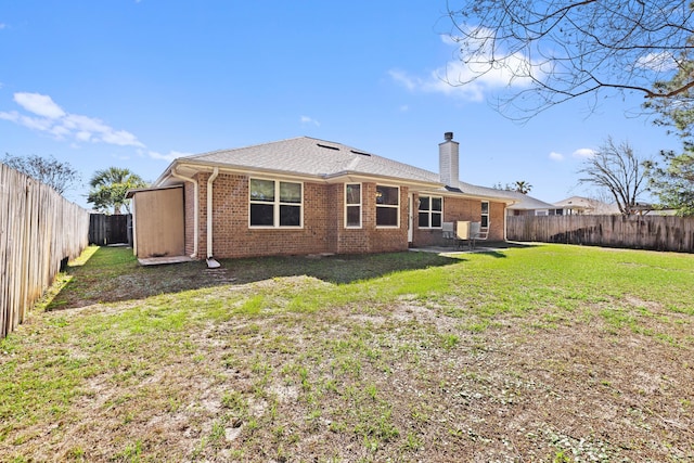 back of house with a patio, a fenced backyard, brick siding, a yard, and a chimney