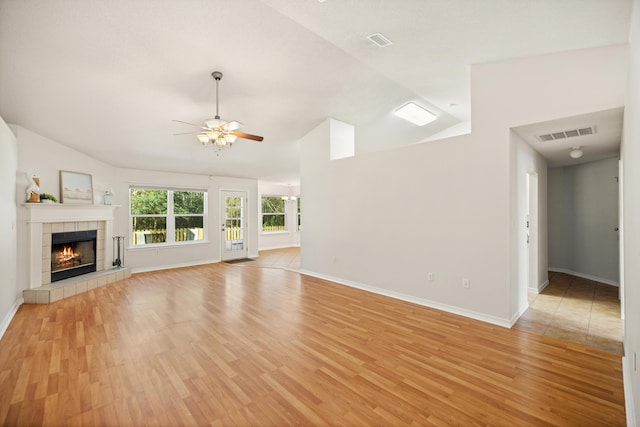 unfurnished living room with light wood-style floors, a fireplace, visible vents, and vaulted ceiling