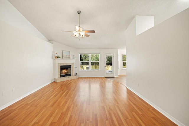 unfurnished living room with a tiled fireplace, light wood-style flooring, and baseboards