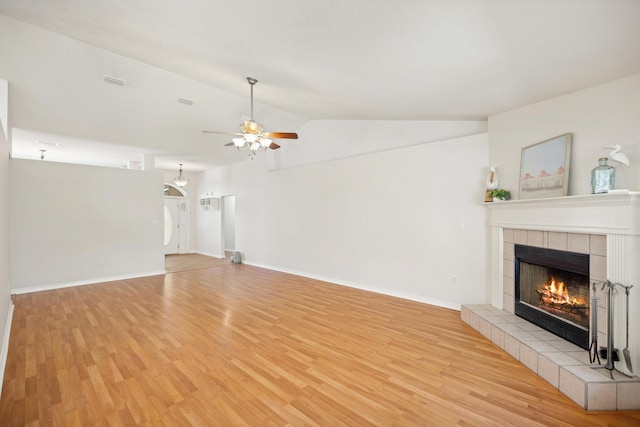 unfurnished living room featuring lofted ceiling, a tile fireplace, ceiling fan, and light wood-style flooring