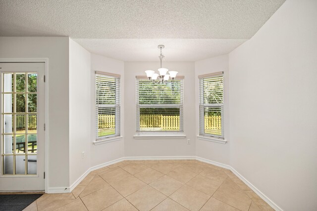 unfurnished dining area with plenty of natural light, light tile patterned flooring, and a notable chandelier