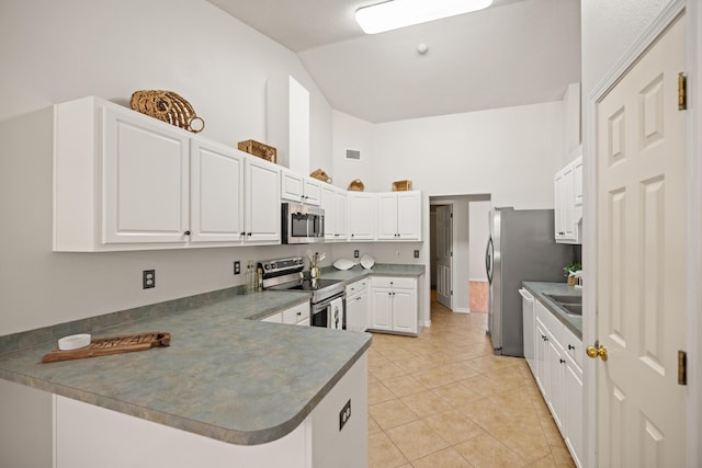 kitchen featuring a peninsula, light tile patterned floors, white cabinetry, and appliances with stainless steel finishes