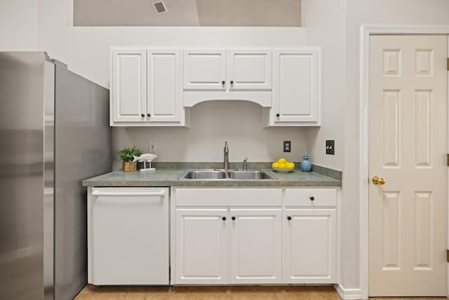 kitchen featuring visible vents, white cabinets, freestanding refrigerator, white dishwasher, and a sink