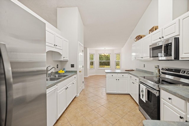 kitchen with a peninsula, stainless steel appliances, white cabinetry, a sink, and light tile patterned flooring