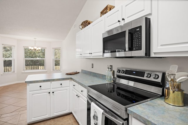 kitchen with appliances with stainless steel finishes, white cabinets, a peninsula, and light tile patterned floors