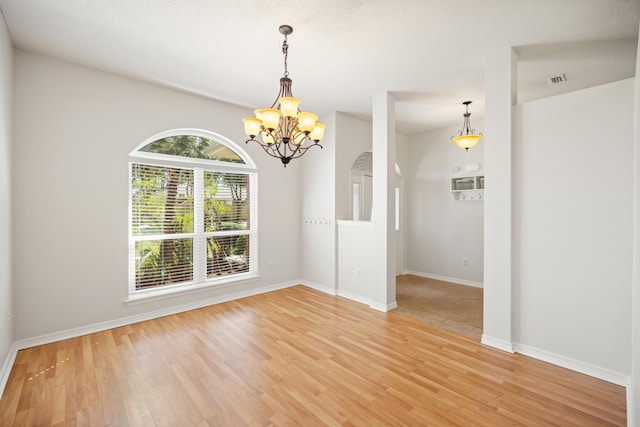 unfurnished dining area featuring a chandelier, light wood-type flooring, and baseboards