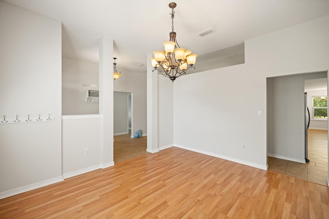 unfurnished room with visible vents, baseboards, light wood-style flooring, and an inviting chandelier