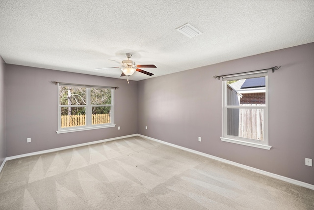 spare room featuring baseboards, a healthy amount of sunlight, visible vents, and light colored carpet